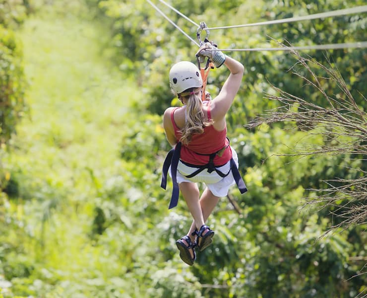 woman ziplining through the jungle