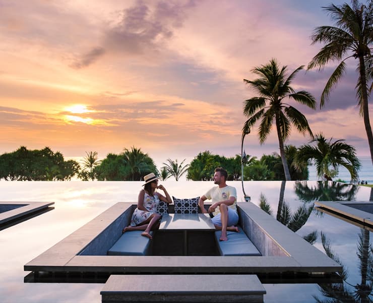 Couple lounging in classy resort pool during sunset