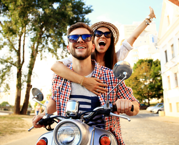 couple riding on a scooter together smiling on vacation