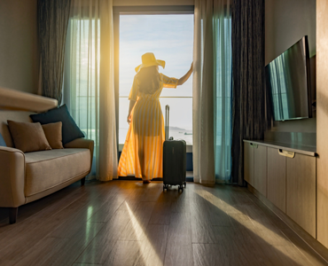 woman gazing out the hotel window with luggage